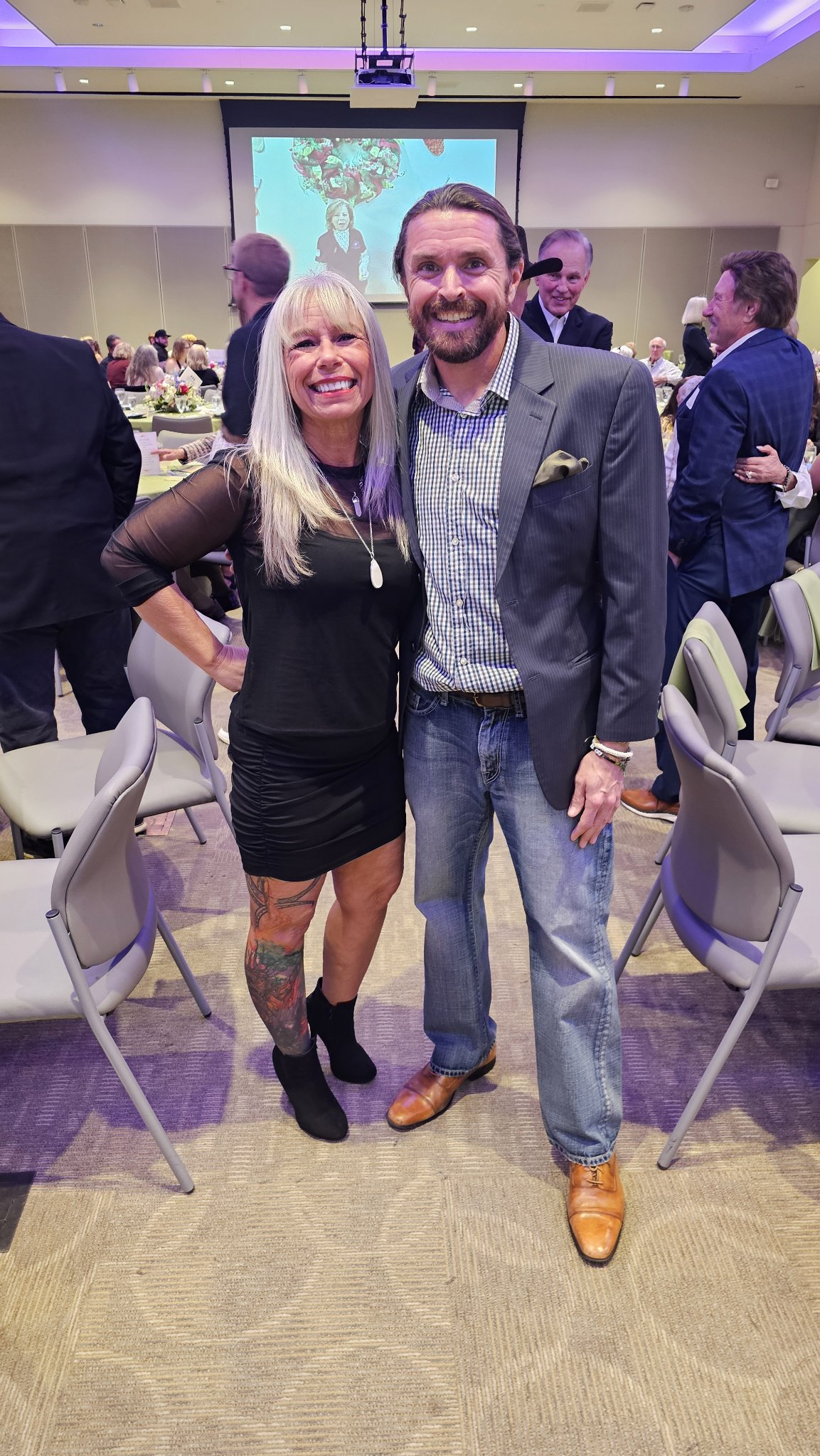 Angel Prater with a guest at a banquet in a purple-lit ballroom