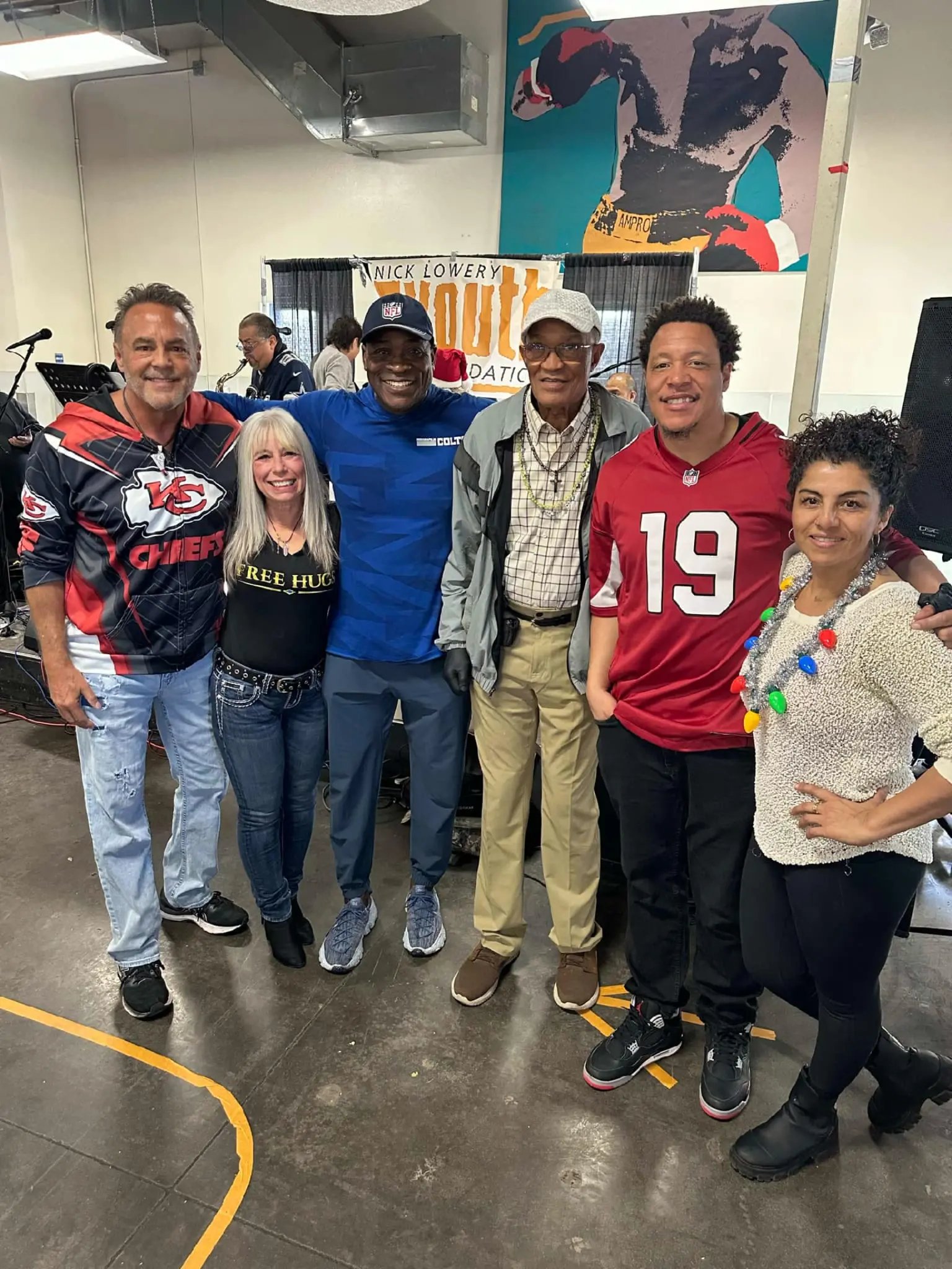 Angel Prater in a FREE HUGS shirt with a group under a Nick Lowery Youth Foundation banner