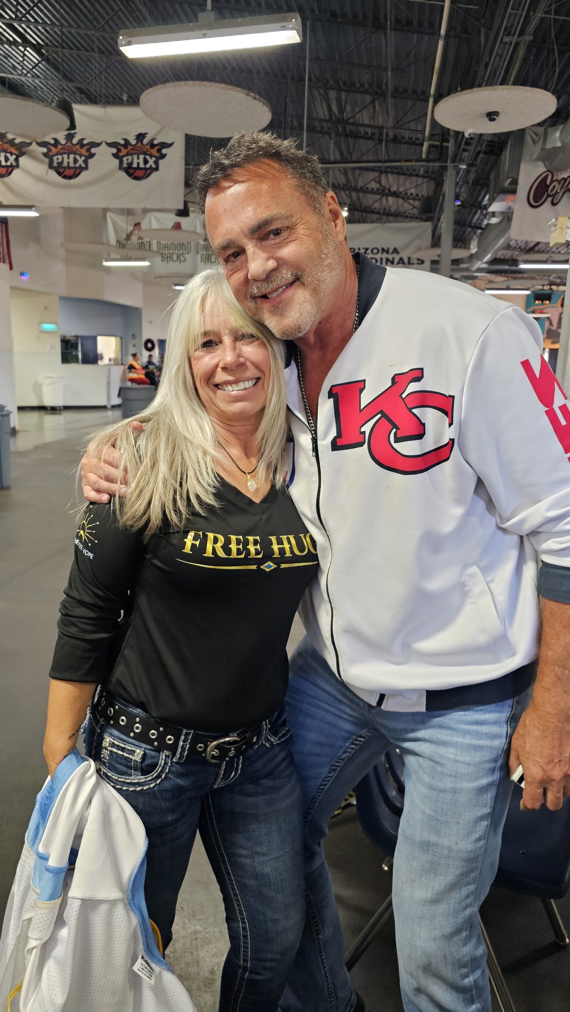 Angel Prater in a FREE HUGS shirt hugged by Nick Lowery in a white KC jacket