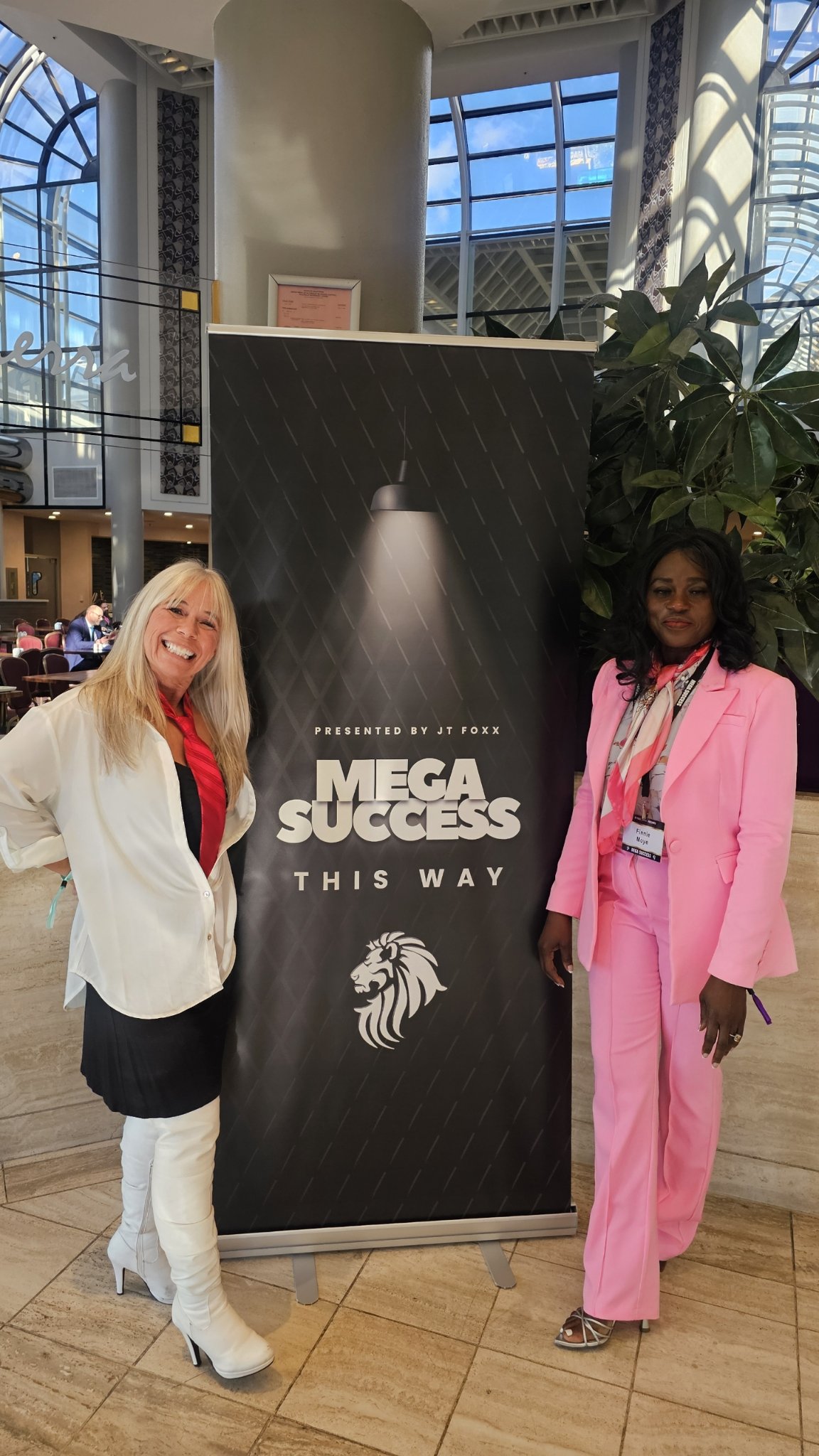 Angel Prater with a fellow attendee beside a Mega Success banner presented by JT Foxx