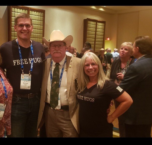 Angel Prater in a FREE HUGS shirt with the U.S. Marshal and a fellow attendee at the National Sheriffs' Association conference in Phoenix, Arizona