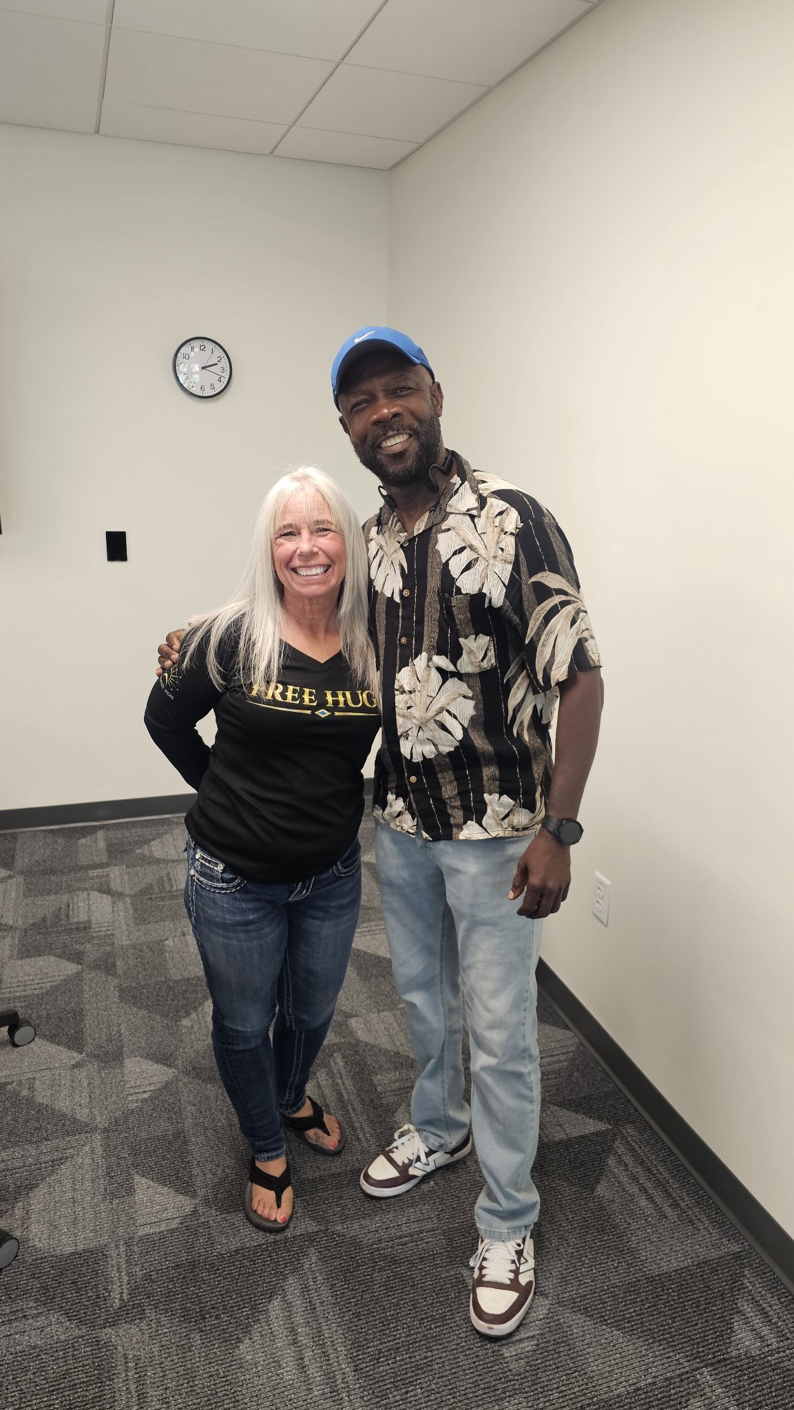 Angel Prater in a FREE HUGS shirt with a fellow attendee in an office