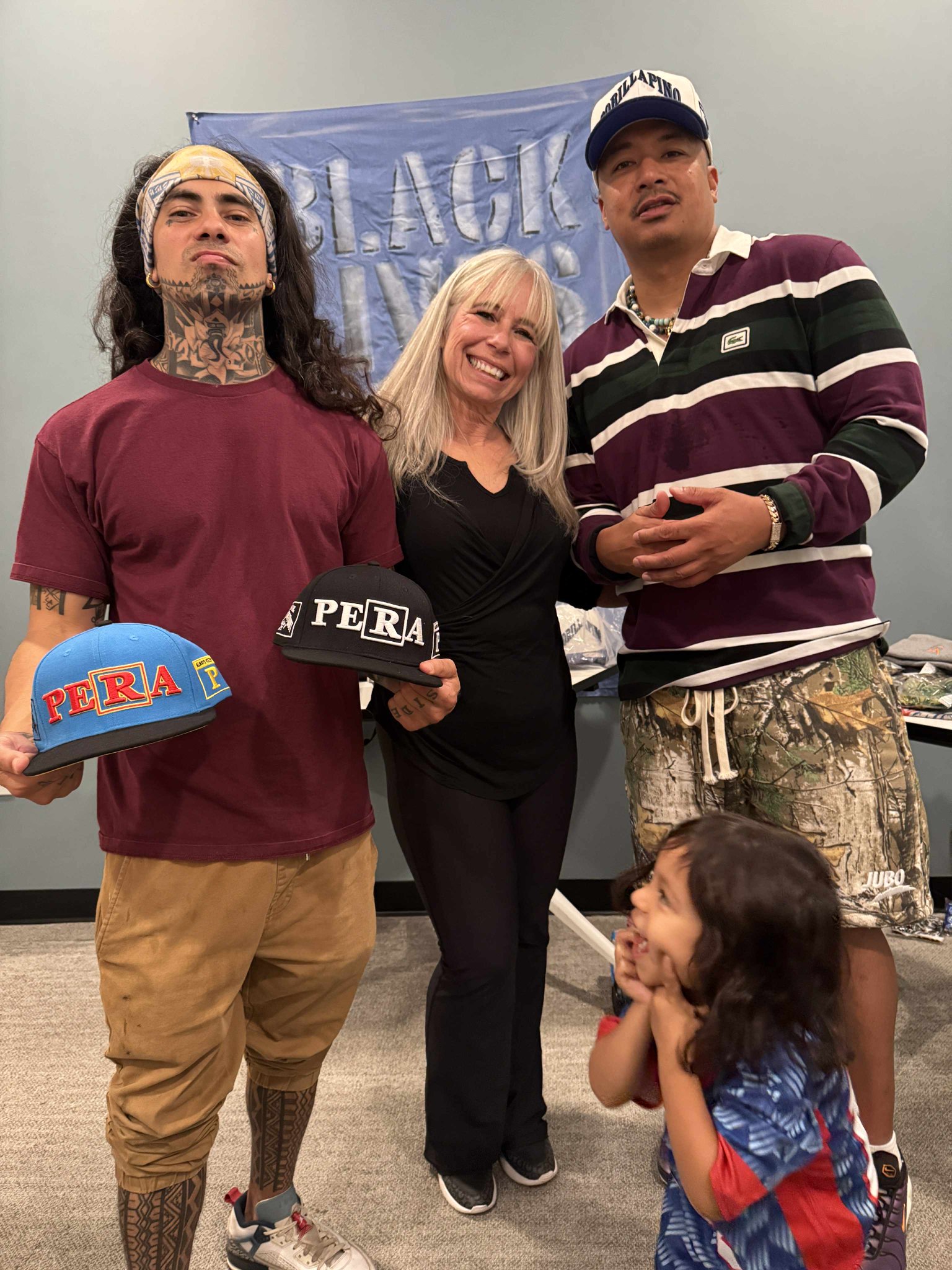 Angel Prater with two community members holding PERA caps