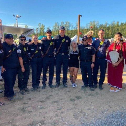 Angel Prater in a FREE HUGS shirt standing in a line with uniformed tribal police officers and community members at a Native American and Indigenous event in Oregon