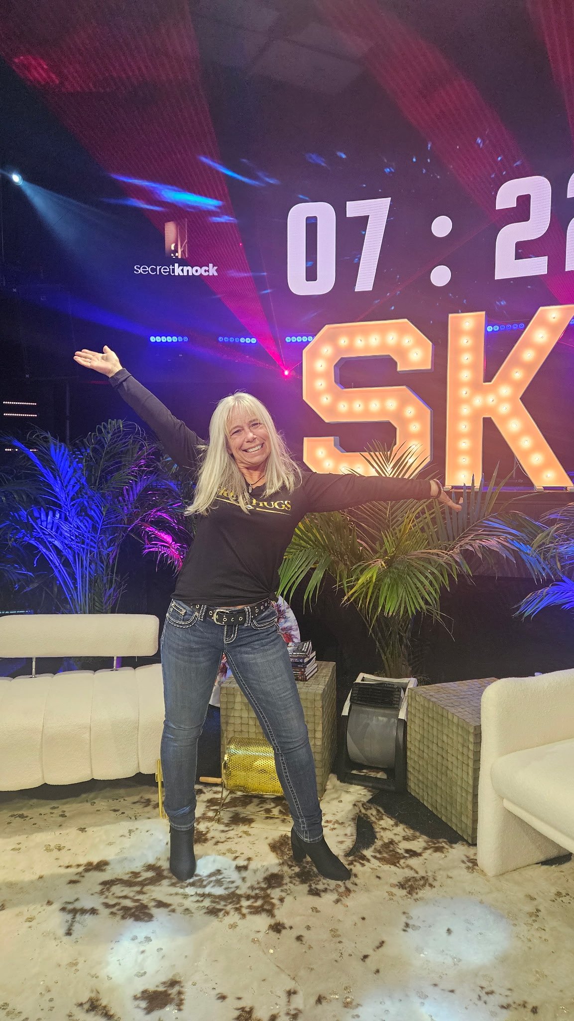 Angel Prater on the Secret Knock stage in front of lit-up SK marquee letters
