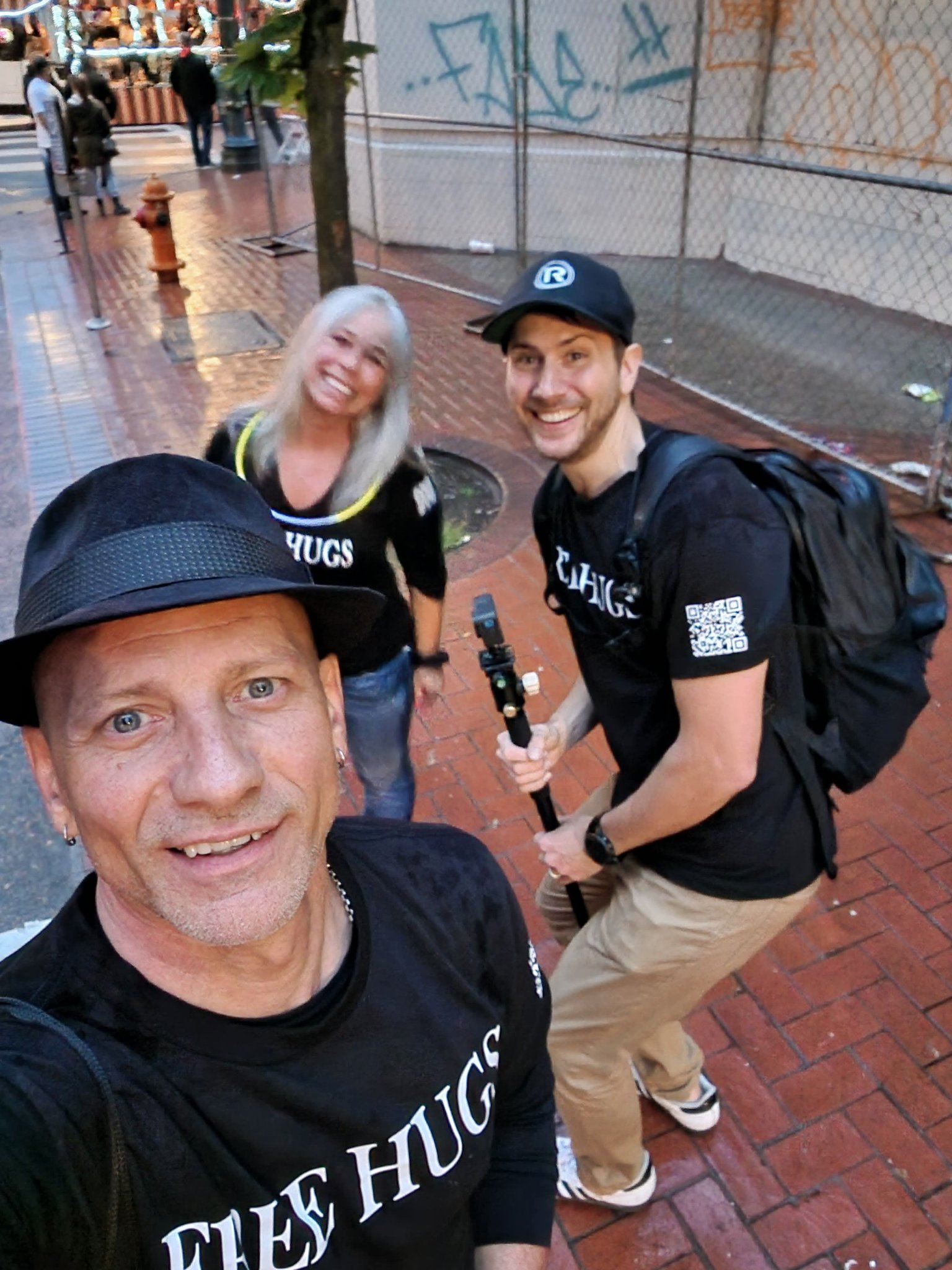 Group selfie at the CareOregon Starlight Parade — Angel Prater with two fellow Free Hugs crew members, all in FREE HUGS shirts