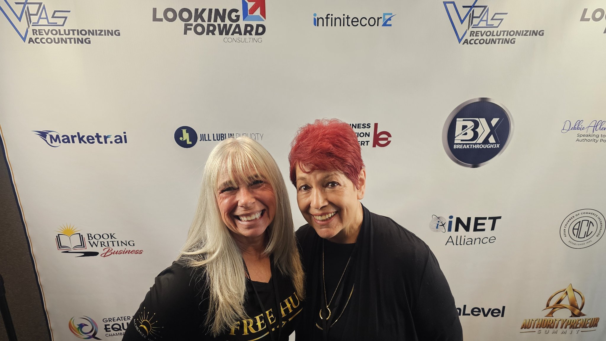 Angel Prater with a fellow attendee in front of an Authoritypreneur Summit backdrop