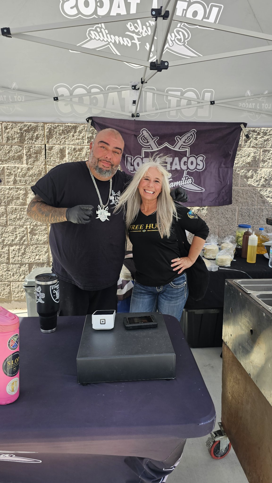 Angel Prater in a FREE HUGS shirt with a vendor at the Lot Tacos — La Familia taco stand