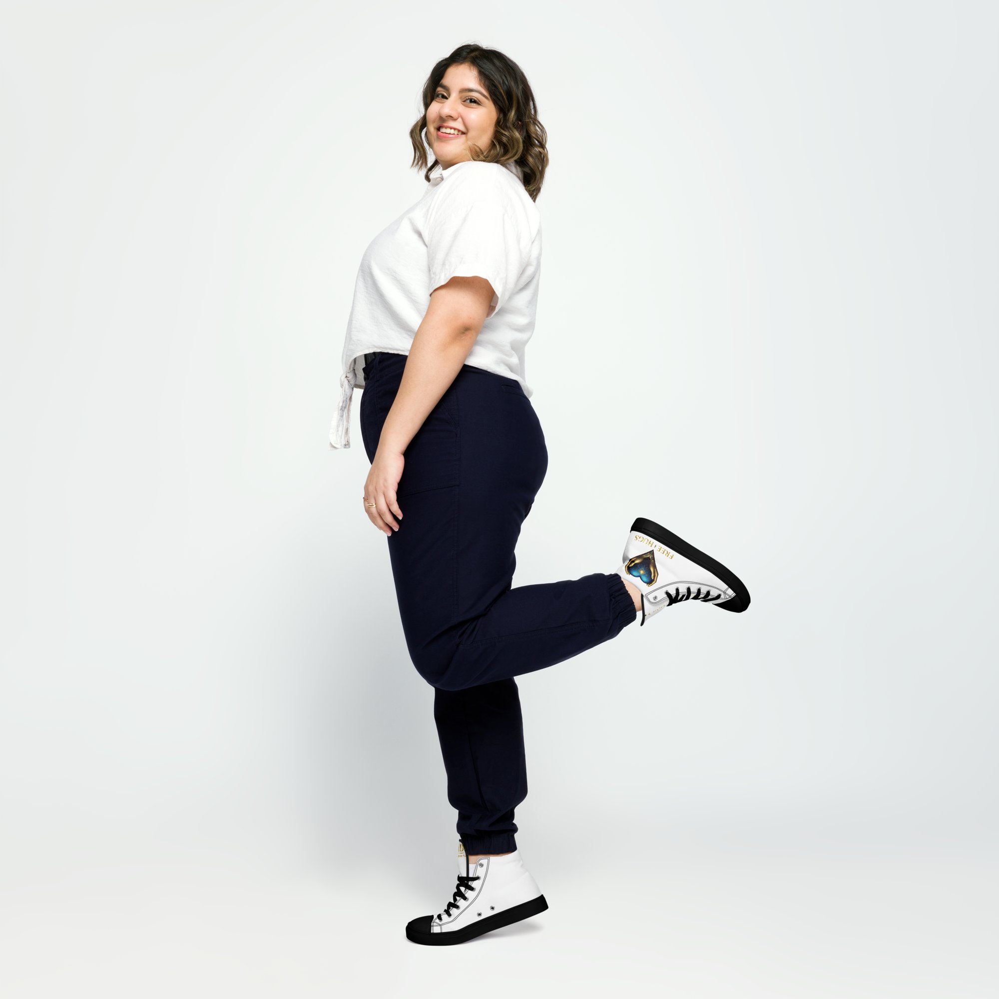 Woman standing with one leg kicked up, wearing the white-and-black FREE HUGS high-top shoes